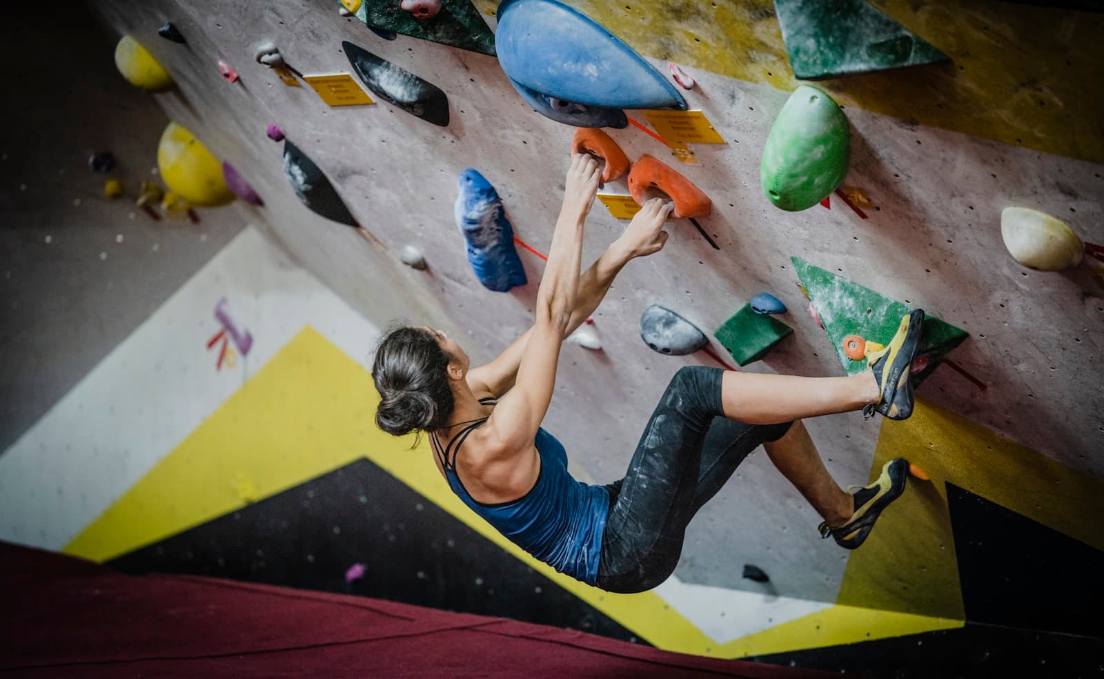 Vrouw die bouldert langs gekleurde grepen in een overdekte klimhal